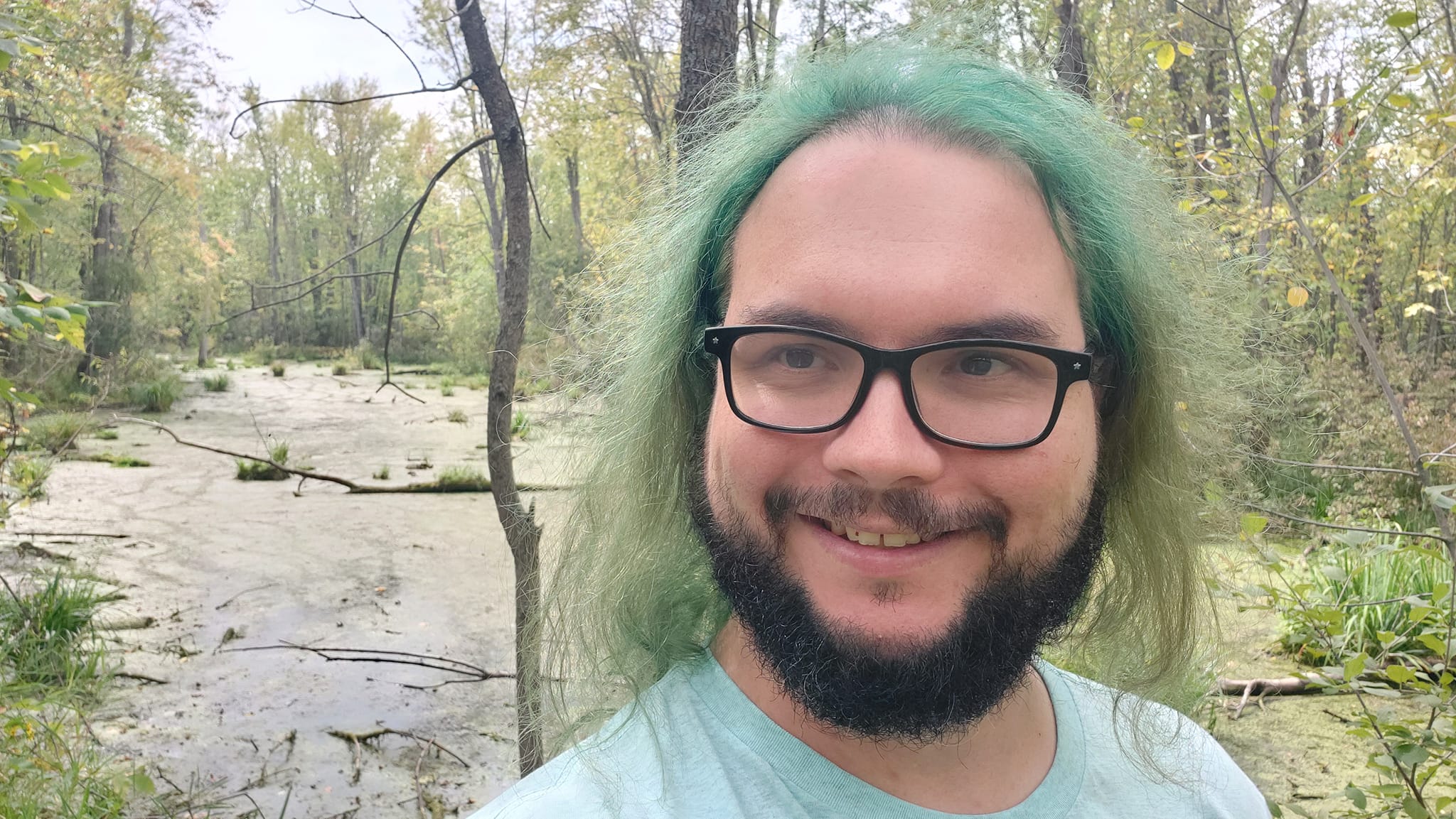 A man with green hair stands in front of a wetland, Photo 2